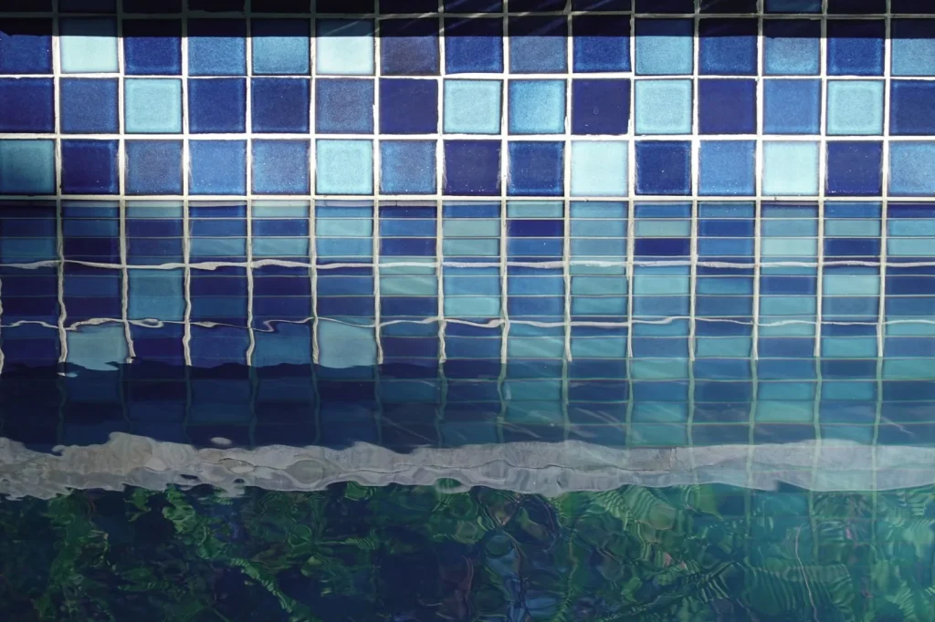 Scum line forming along the waterline tiles of a backyard pool