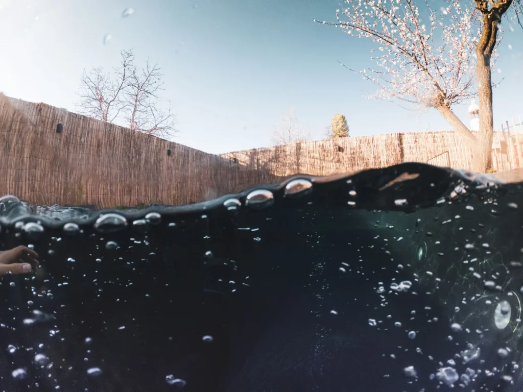 Robotic pool cleaner crawling along a pool floor with exhaust bubbles rising