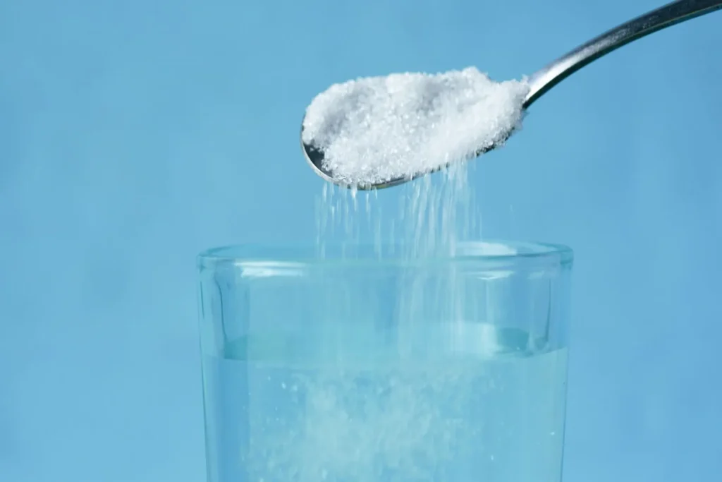 Pool shock granules pouring into blue swimming pool water