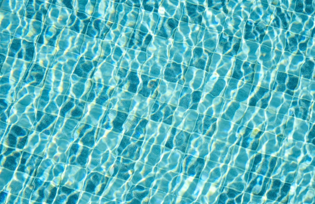 Robotic pool cleaner gripping a tiled pool wall below the surface
