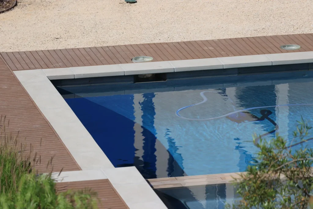 Long blue cleaner cable laid out straight on a sunlit pool deck to relax