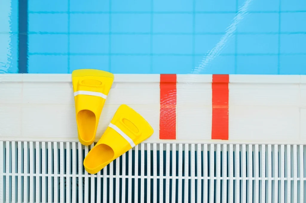 Robot cleaner caddy with loosely coiled cable parked in shade beside a pool