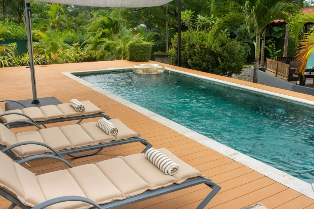 Robotic pool cleaner resting dry on a sunlit pool deck beside its charging cable