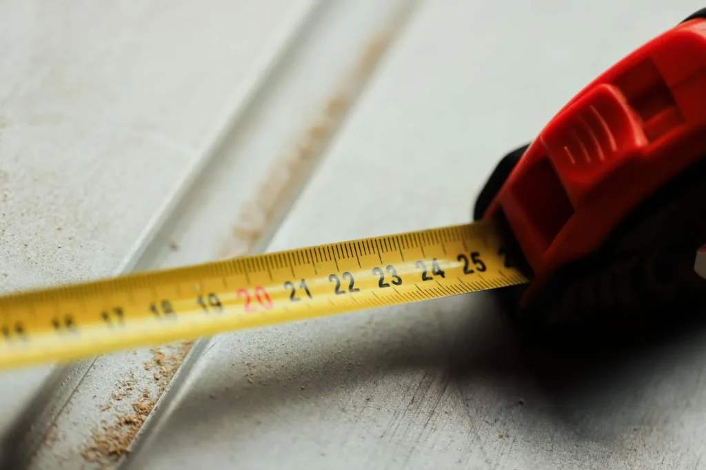 Tape measure stretched along the coping edge of a backyard swimming pool