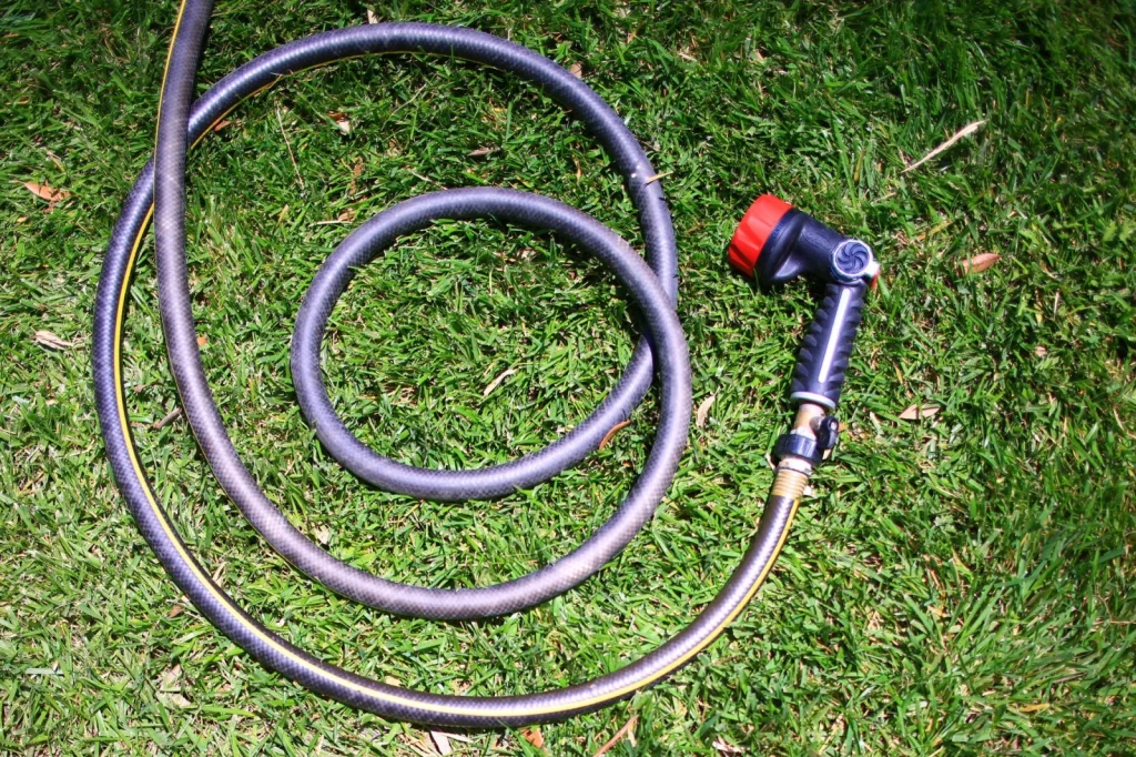 Garden hose rinsing pool cleaning equipment on a stone patio