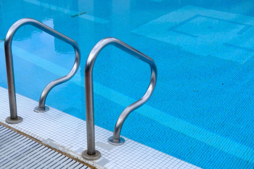Stainless ladder rails and steps descending into clear blue pool water