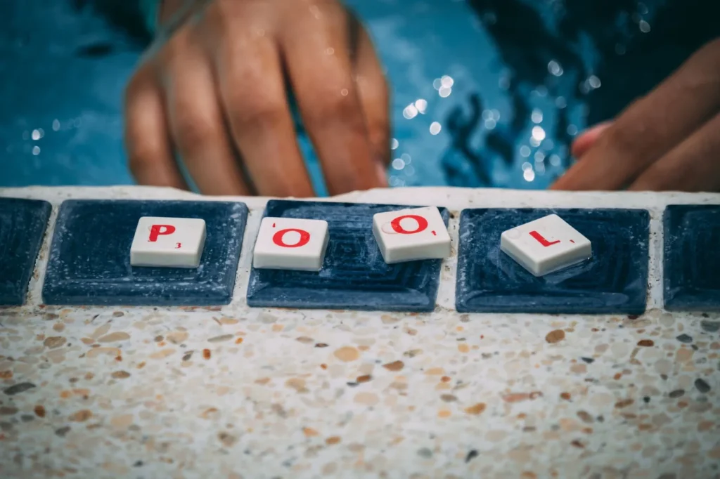 Gloved hand scrubbing the tile line of a pool with a sponge